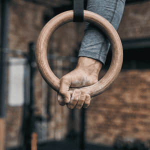 A close-up shot of an athlete's chalked hand gripping a wooden gymnastics ring