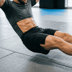 Close-up of an athlete in a rash guard holding a hollow body position on gym mats