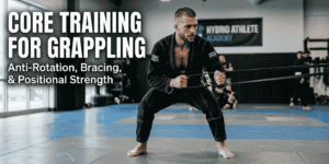 Grappler in a black gi performing a standing cable anti-rotation press on jiu-jitsu mats