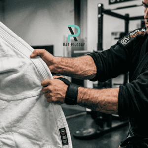 Grappler's forearm gripping a gi with a lifting strap