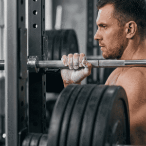 Close-up of a focused lifter with a chalked hand gripping a heavily loaded barbell in a rack